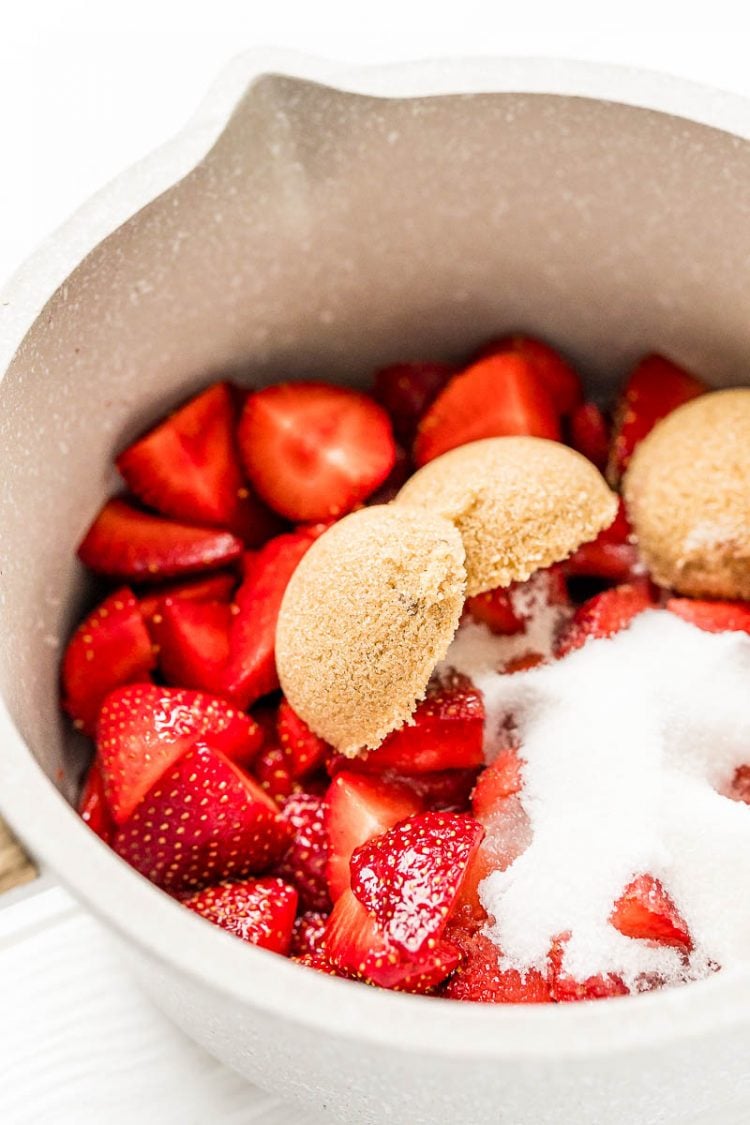 Ingredients to make strawberry sauce in a small saucepan.