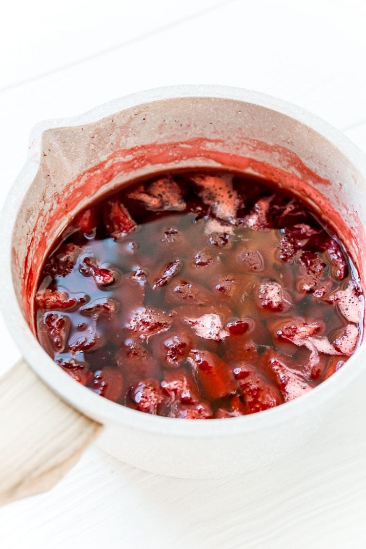 Strawberries that have been boiled in a small pot.