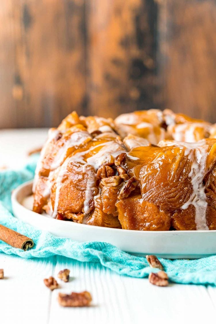 Monkey bread on a white plate on a teal napkin with pecans scattered around.