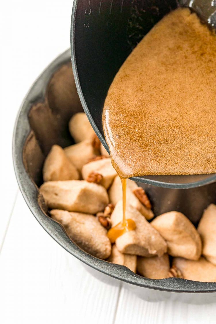 monkey bread sauce being poured into the pan over biscuits.