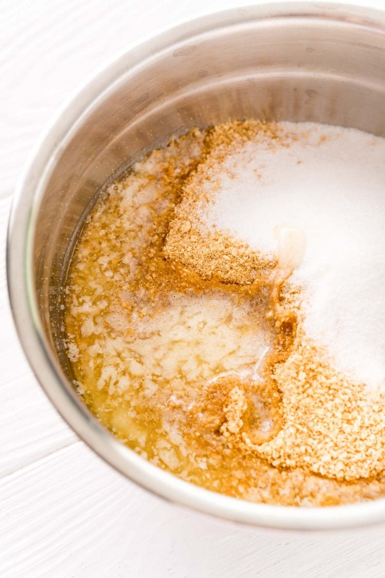 Ingredients to make a graham cracker crust in a metal mixing bowl.