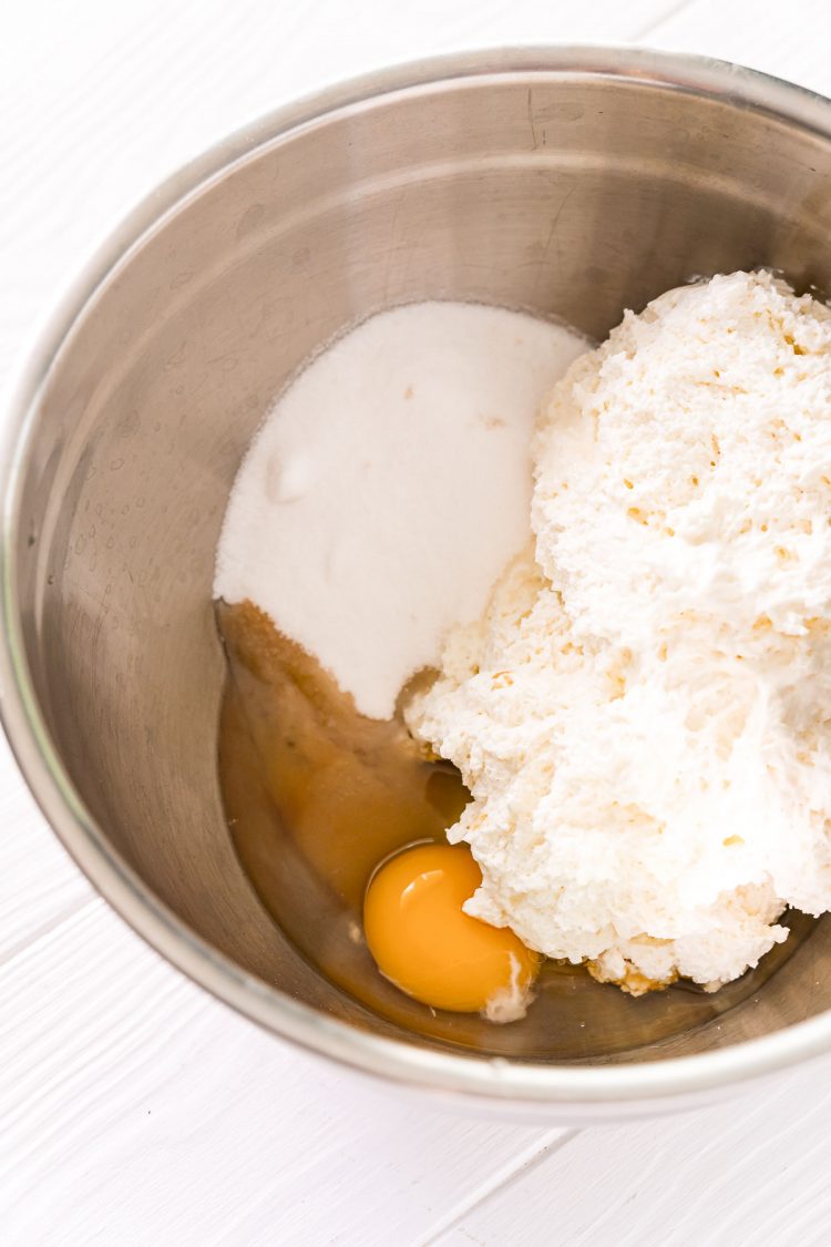 Ingredients to make a cheesecake filling in a metal mixing bowl.