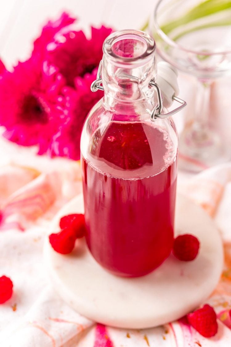 Angled overhead photo of a glass bottle of raspberry simple syrup.