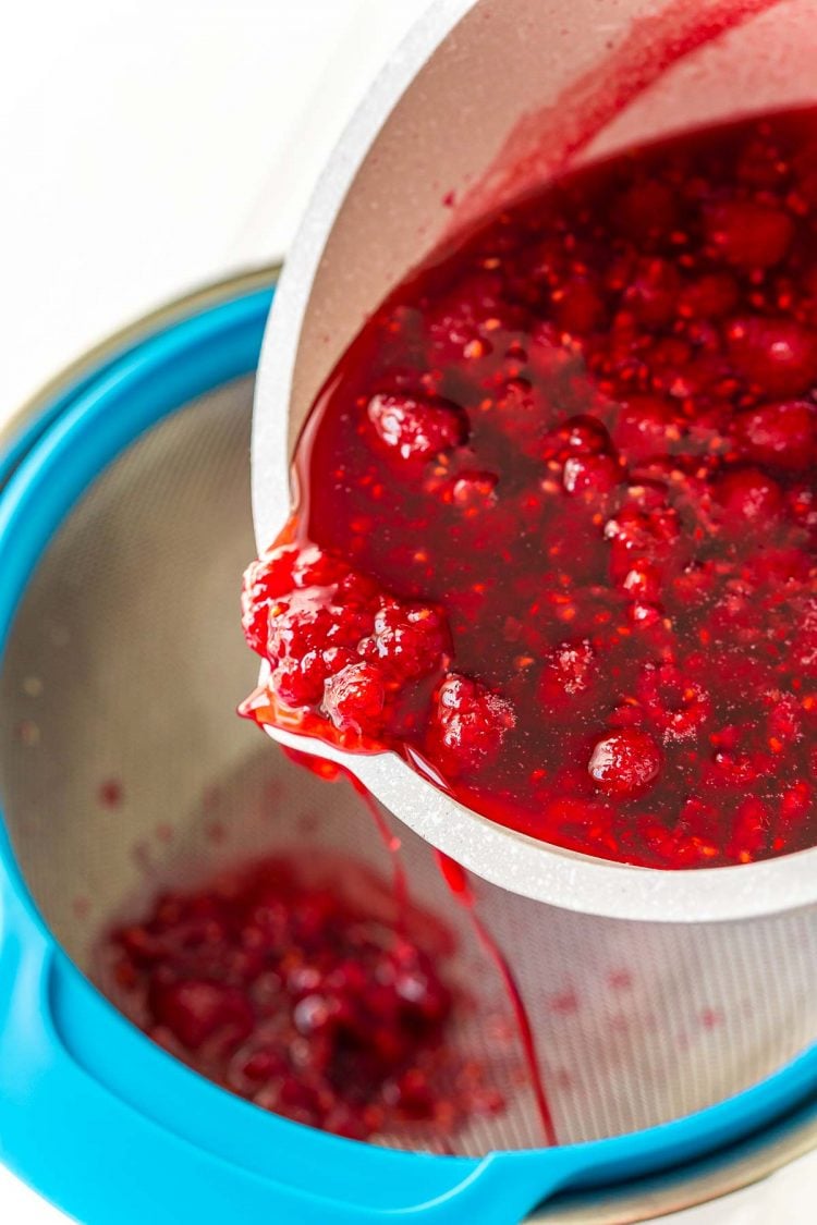 Raspberries being run through a fine mesh strainer to make simple syrup.