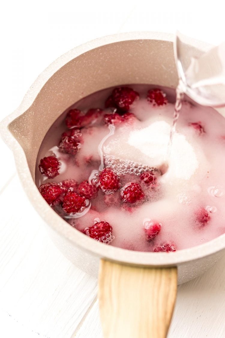 Ingredients being added to a pot to make raspberry simple syrup.