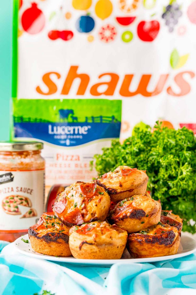 Mini pizzas in a white plate with ingredients in the background.