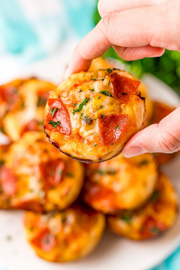 Woman's hand holding a mini pizza.