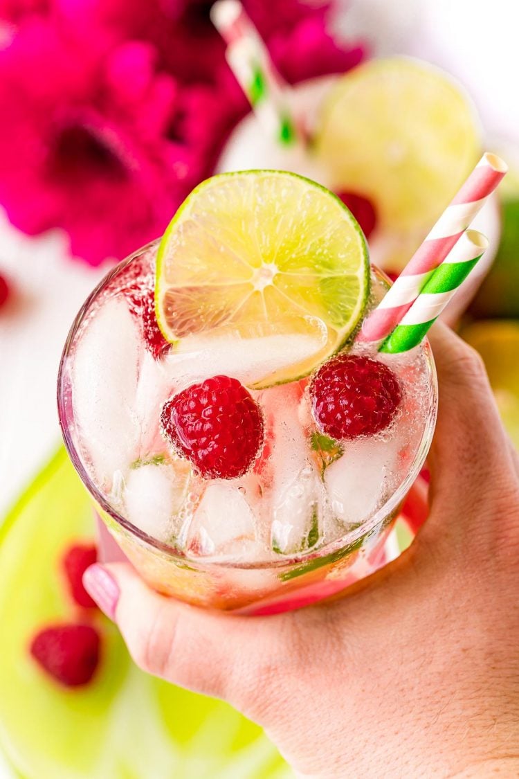 Woman's hand holding a raspberry lime rickey to the camera.