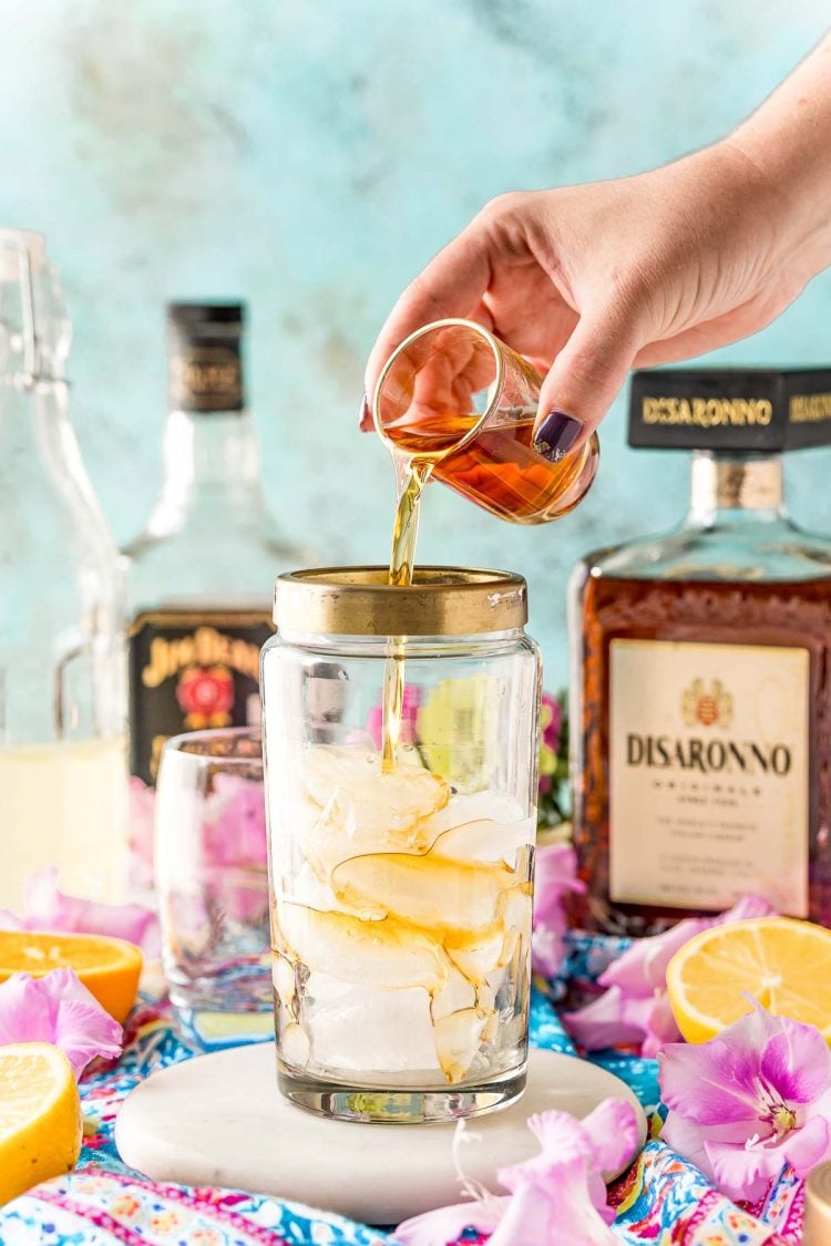 Amaretto being added to a cocktail shaker with ice.
