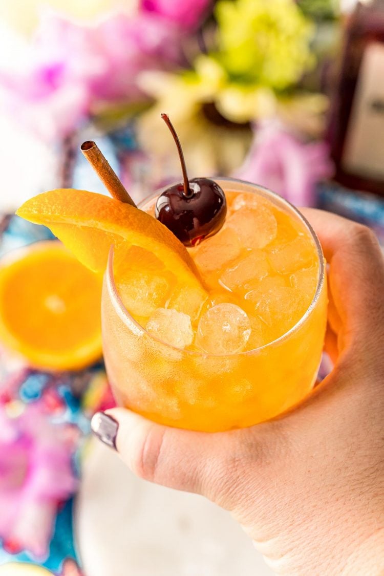 Woman's hand holding an Amaretto Sour up to the camera.