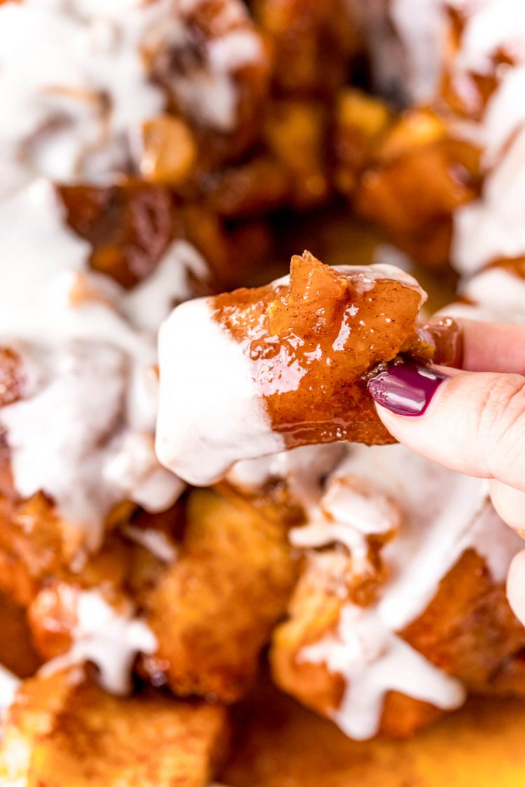 A woman's hand pulling a piece of monkey bread away from the loaf.