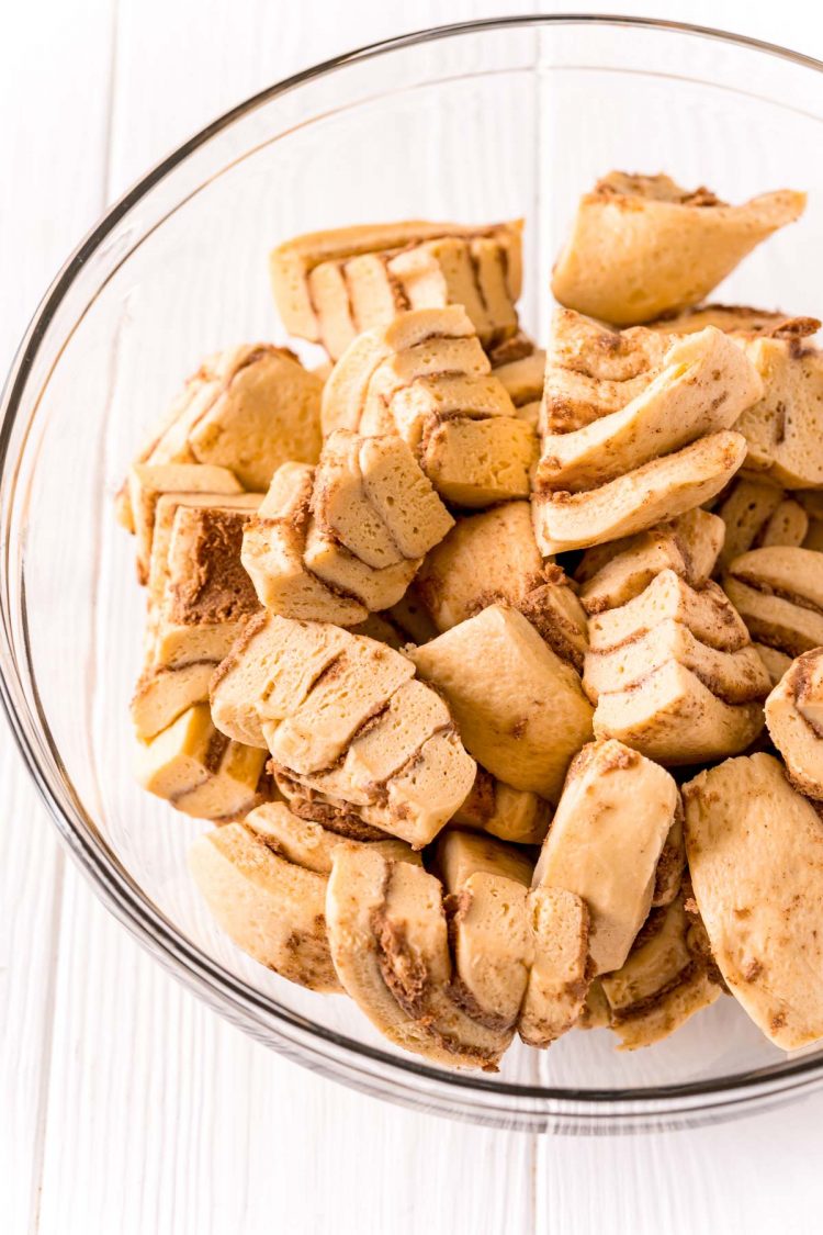 Chopped cinnamon rolls in a glass mixing bowl.