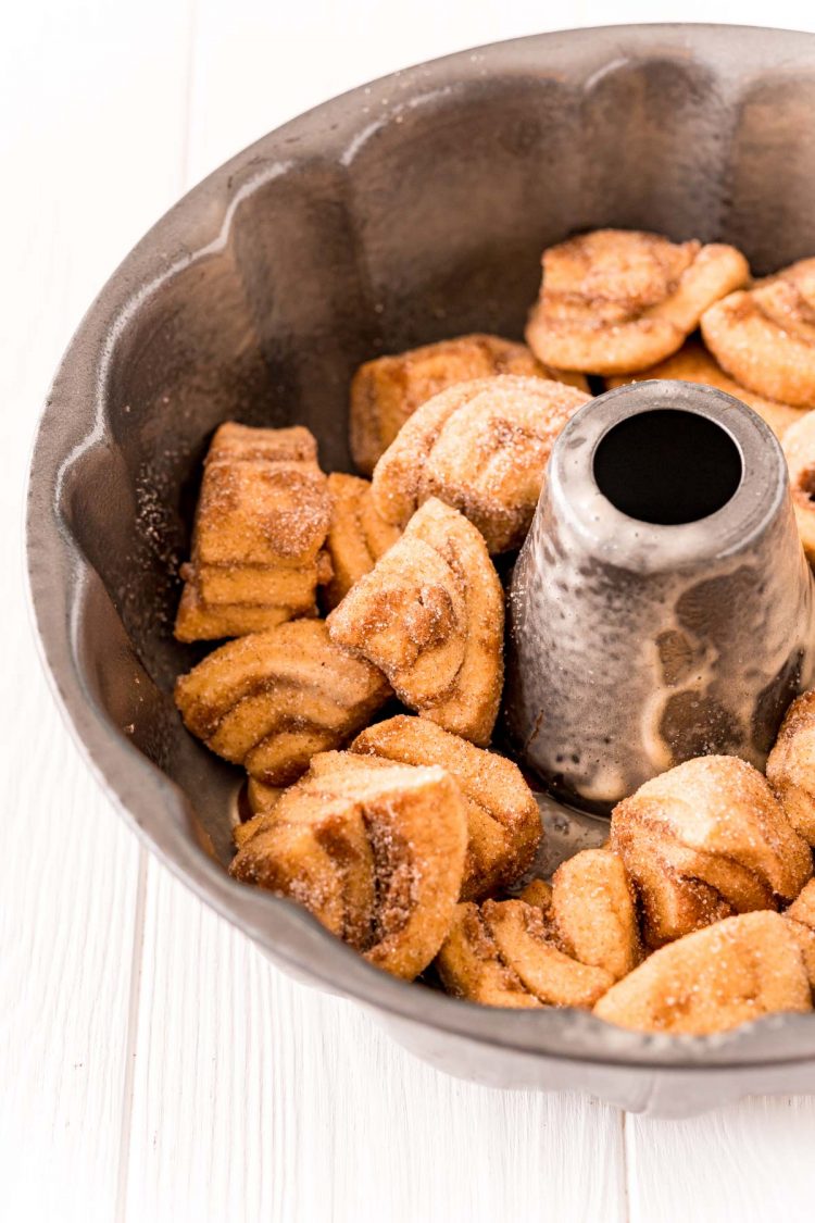 Quartered cinnamon rolls coated in cinnamon sugar in a bundt pan to make monkey bread.