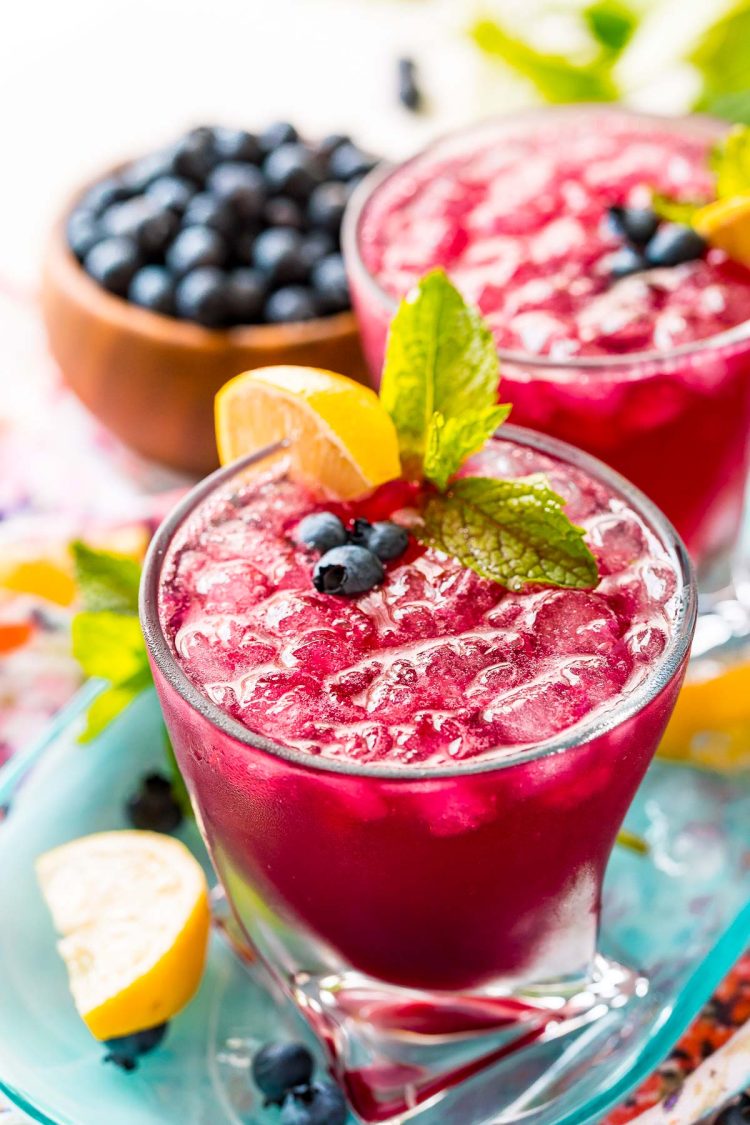 Close up photo of a glass filled with a blueberry cocktail.