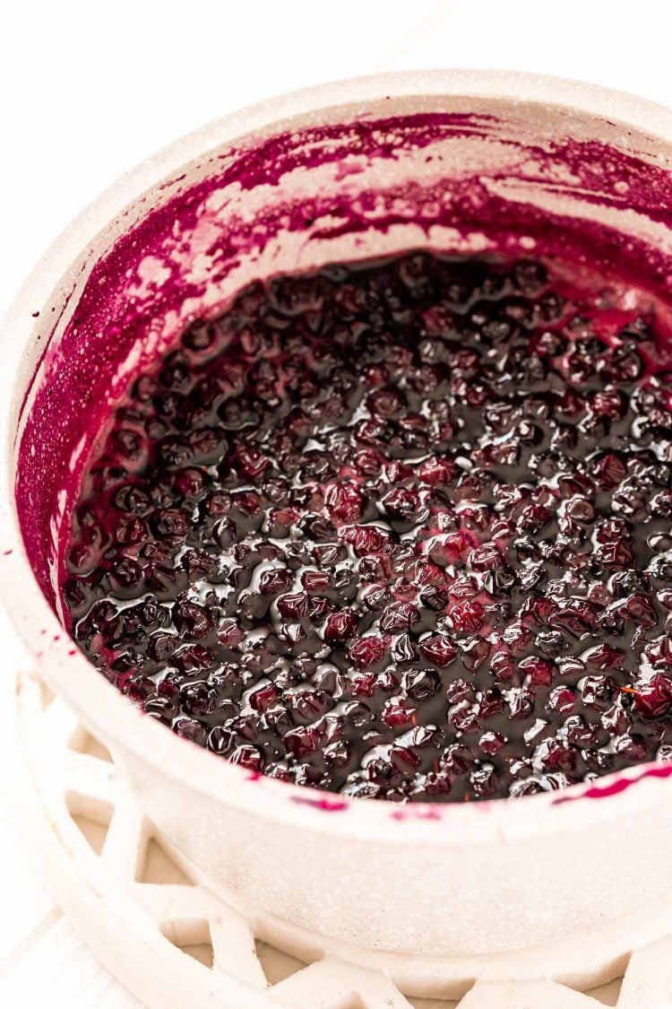 Blueberries, sugar, and water, simmering in a small saucepan to make simple syrup.