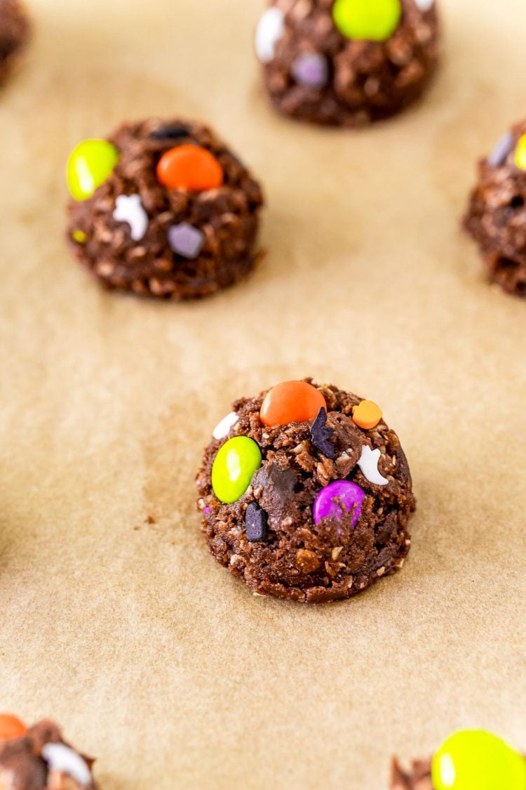 Balls of chocolate cookies dough with halloween sprinkles on parchment paper.