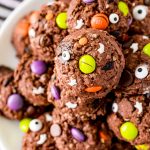 Close up photo of Halloween Monster cookies on a white plate on a black and white striped napkin.