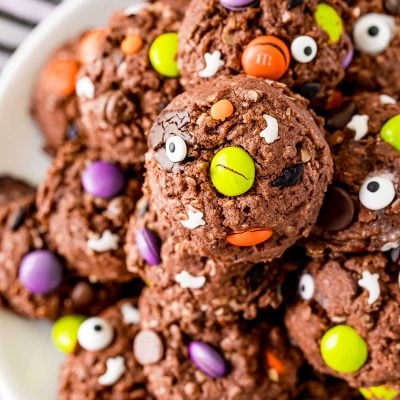 Close up photo of Halloween Monster cookies on a white plate on a black and white striped napkin.