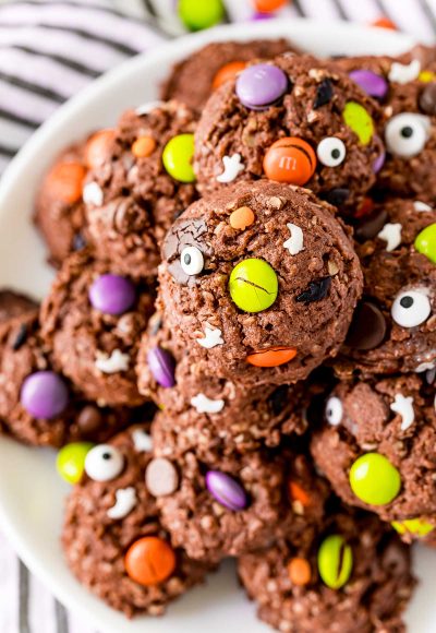 Close up photo of Halloween Monster cookies on a white plate on a black and white striped napkin.