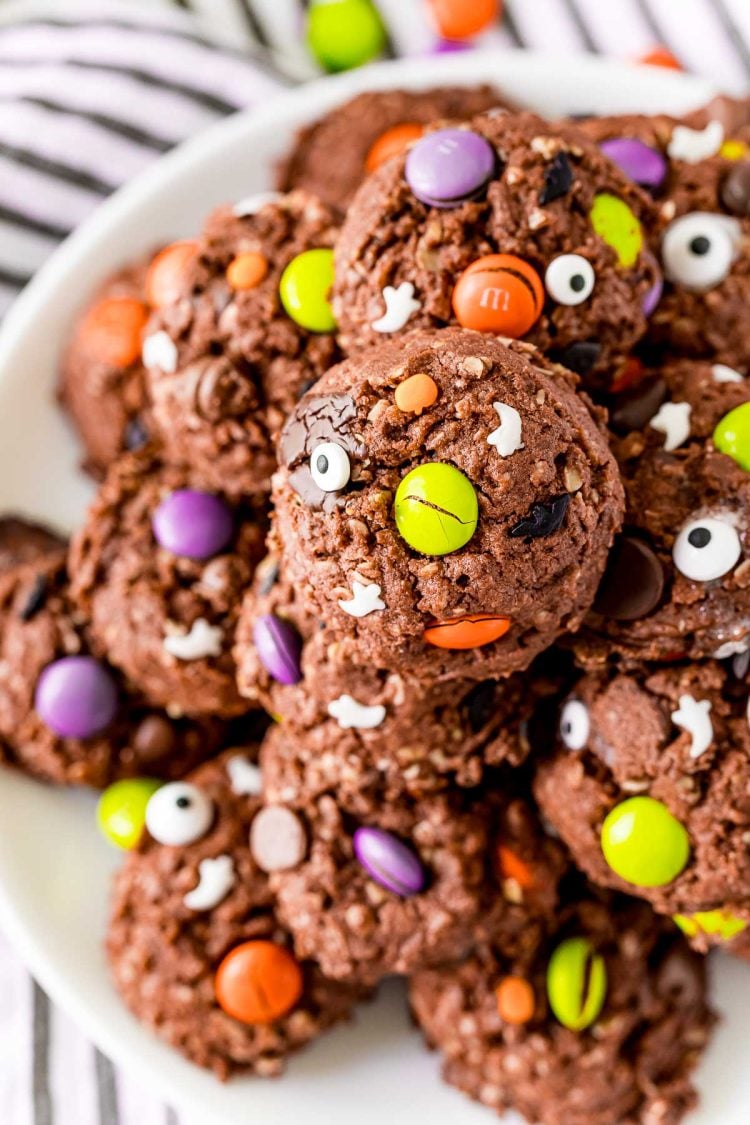 Close up photo of Halloween Monster cookies on a white plate on a black and white striped napkin.