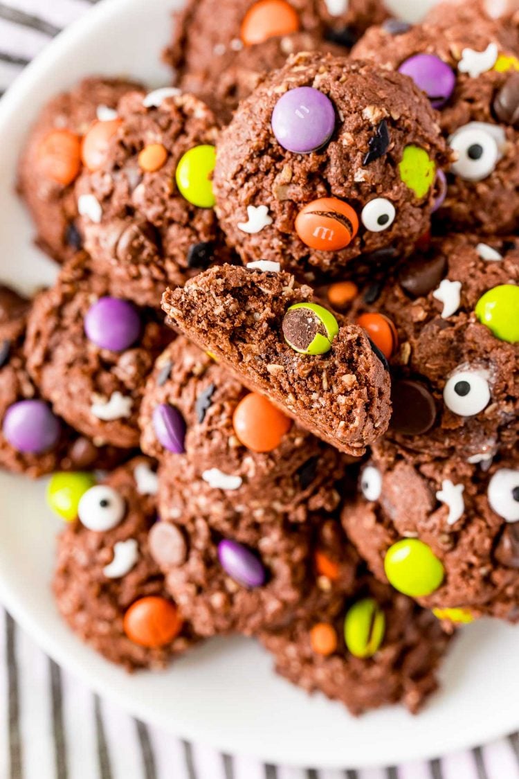 Close up photo of chocolate halloween cookies on a white plate. One of the cookies has a bite taken out of it.