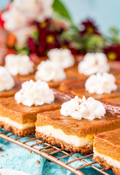 Close up photo of pumpkin pie cheesecake bars on a wire rack.