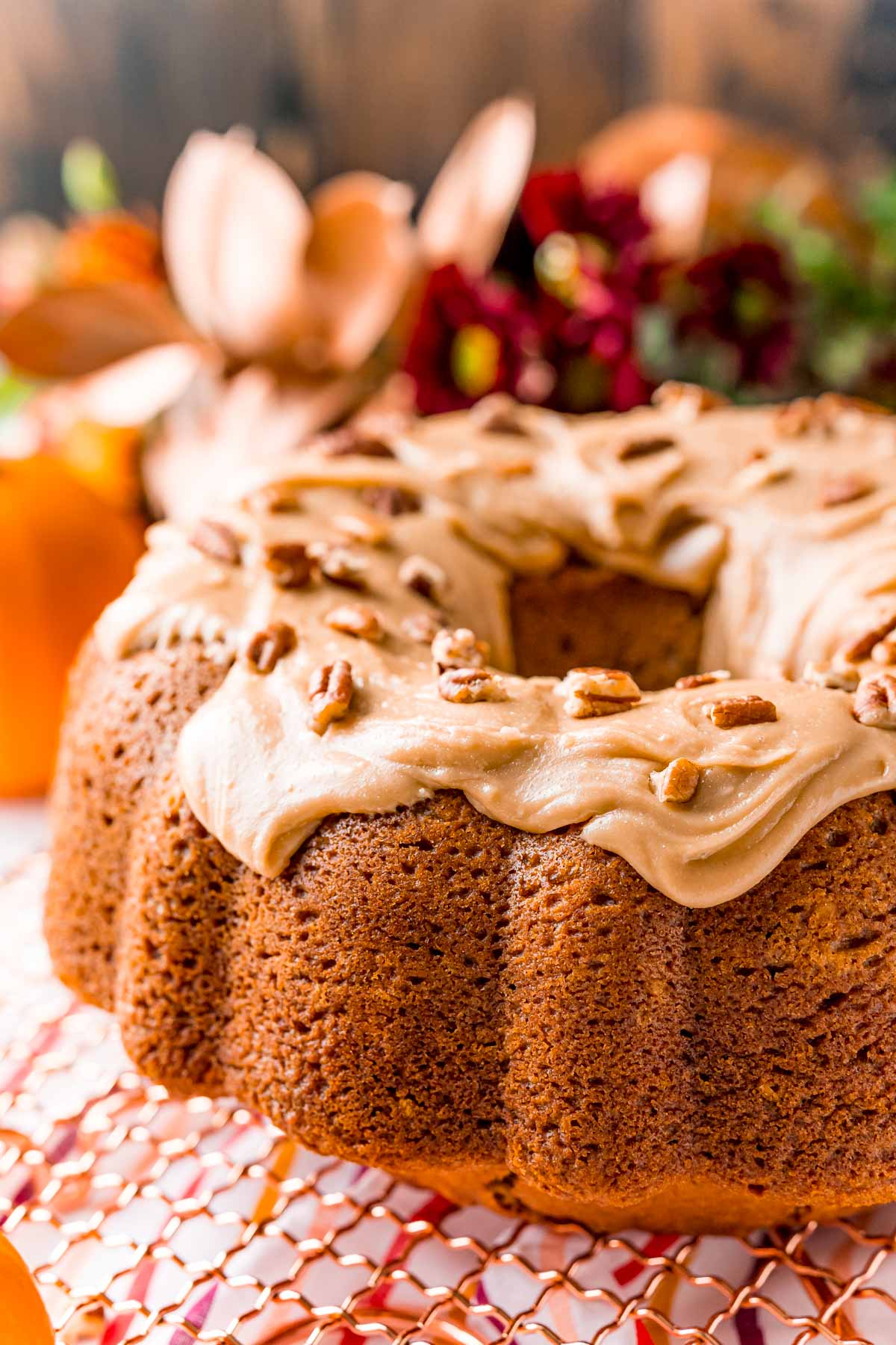 Close up photo of an iced pumpkin bundt cake on a gold wire rack.