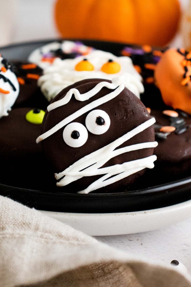 Close up photo of Halloween decorate oreos on a black plate.