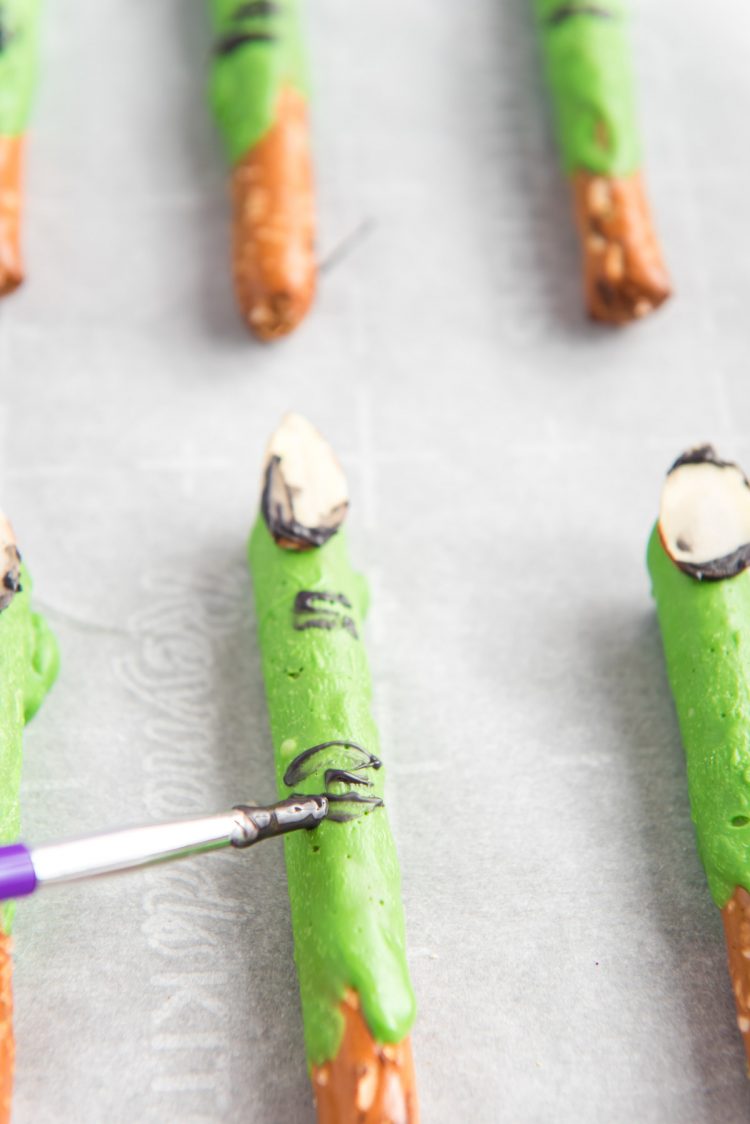 Witch finger pretzel rods being painted.