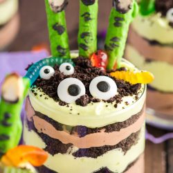 Close up photo of layers Halloween dirt cups with pretzel stick witch fingers, candy eyes, and gummy worms.