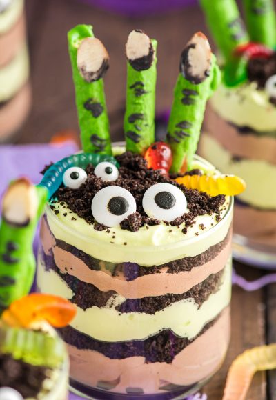 Close up photo of layers Halloween dirt cups with pretzel stick witch fingers, candy eyes, and gummy worms.