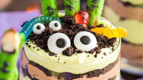 Close up photo of layers Halloween dirt cups with pretzel stick witch fingers, candy eyes, and gummy worms.