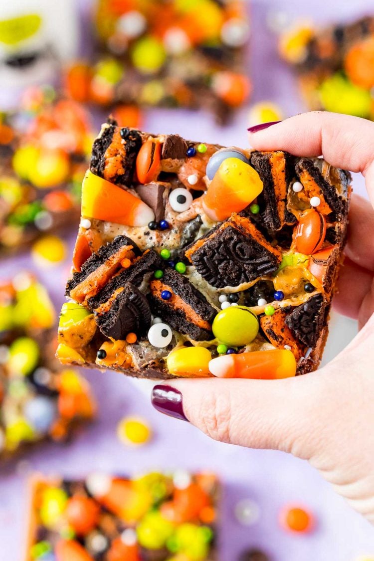 Woman's hand holding a halloween cookie bar towards the camera.