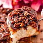 Close up photo of a pecan sticky bun being pulled away from the rest on a serving spoon.