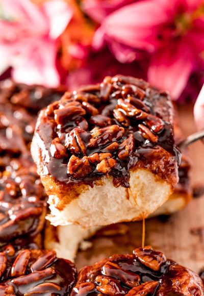 Close up photo of a pecan sticky bun being pulled away from the rest on a serving spoon.