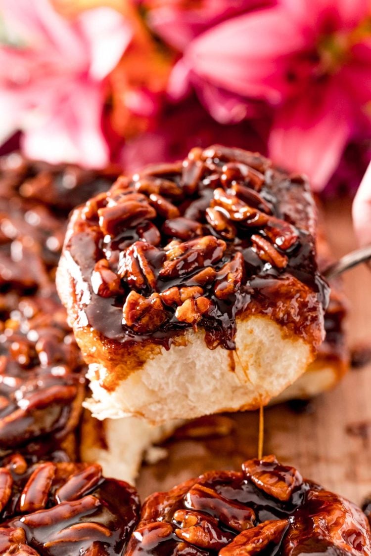 Close up photo of a pecan sticky bun being pulled away from the rest on a serving spoon.