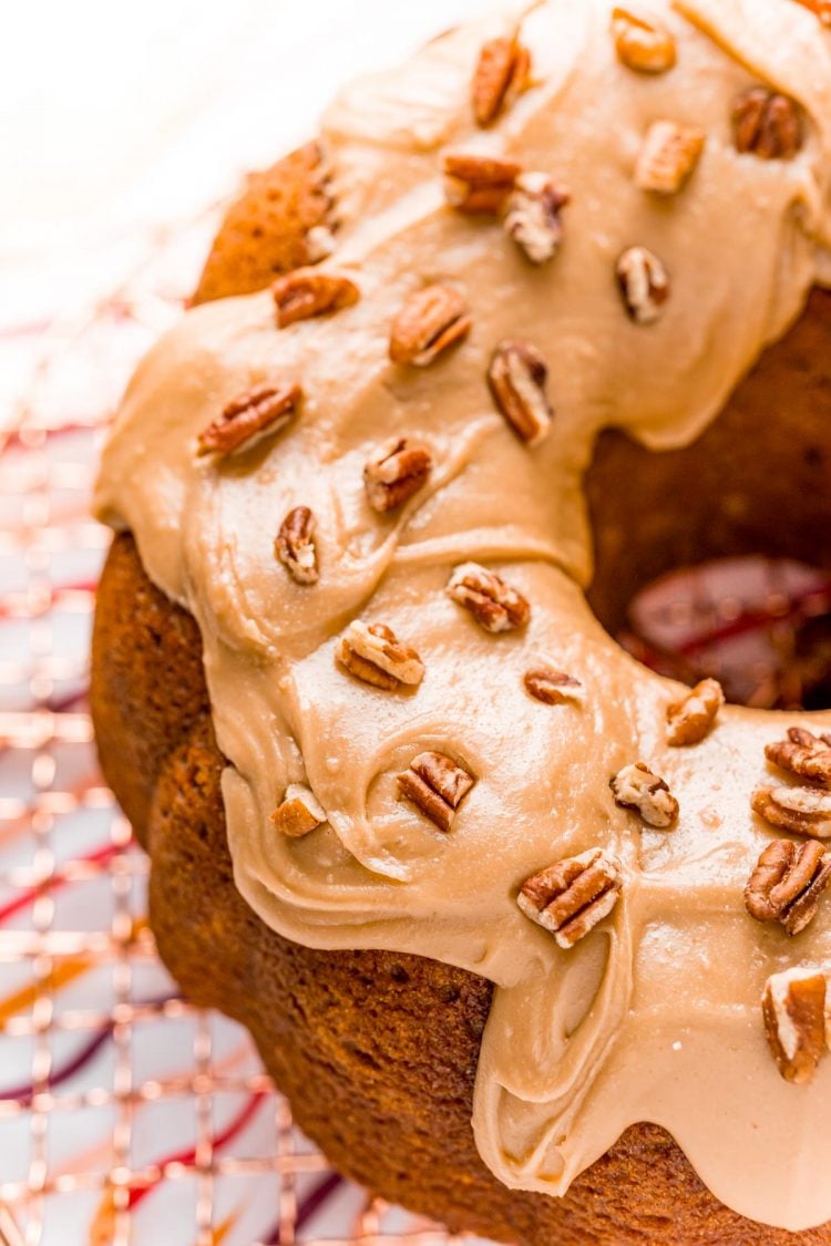 Close up photo of a pumpkin pound cake with icing on it topped with pecans.