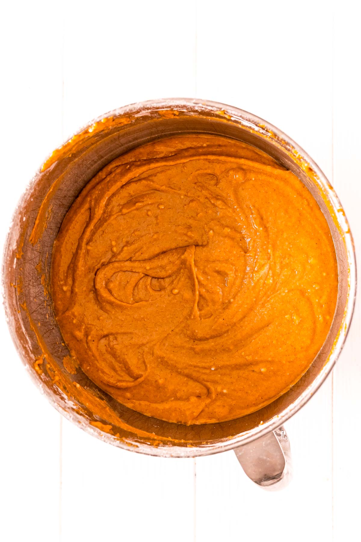 Overhead photo of pumpkin cake batter in a stainless steel mixing bowl.