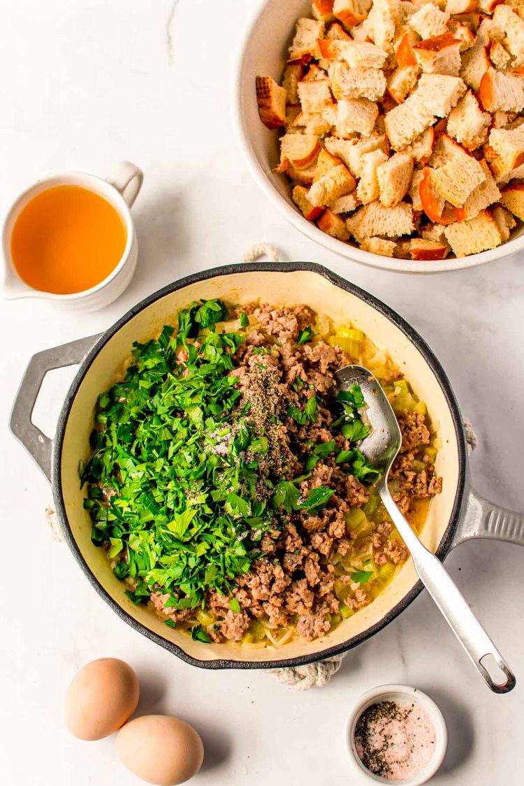 Overhead photo of ground sausage and herbs being cooked in a skillet.