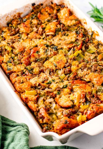 Close up photo of sausage stuffing in a white baking dish with a green napkin next to it.