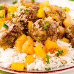 Close up photo of sweet and sour meatballs on a bed of white rice with pineapple.