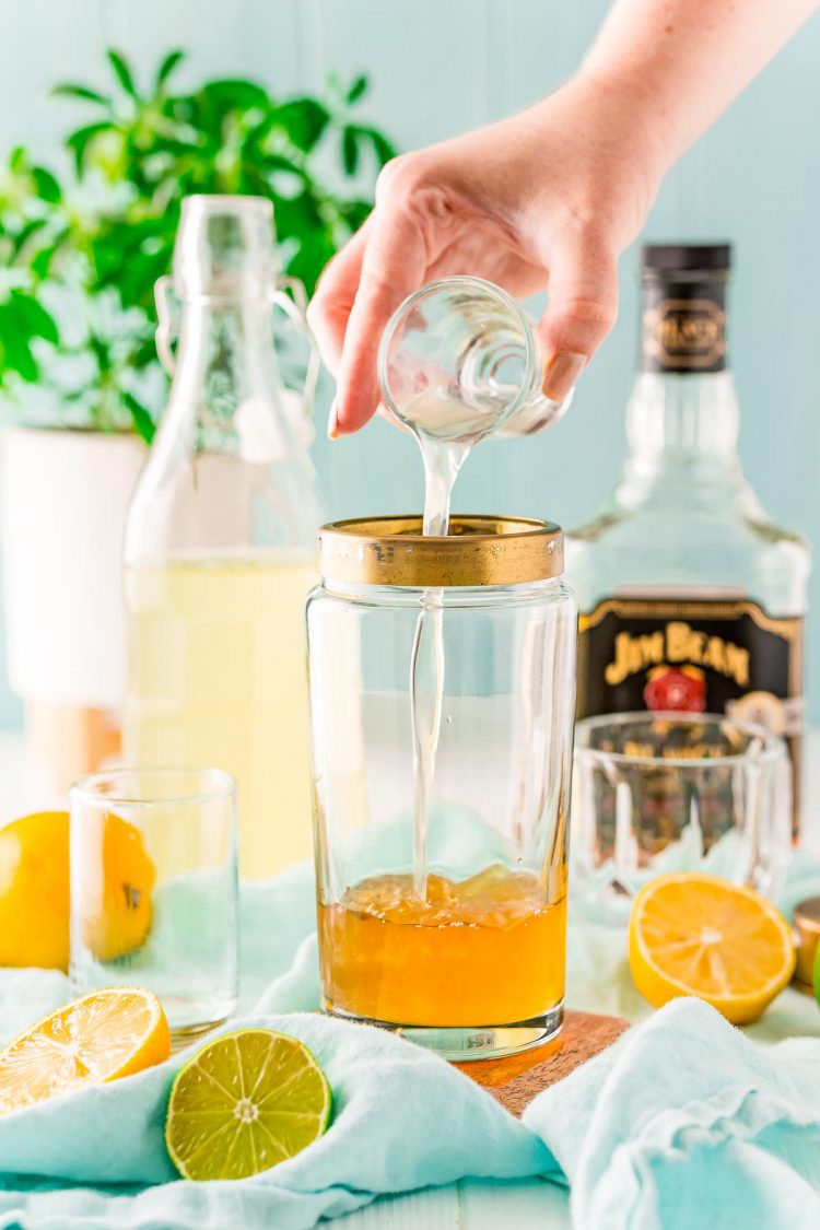 Sweet and sour mix being added to a cocktail shaker.