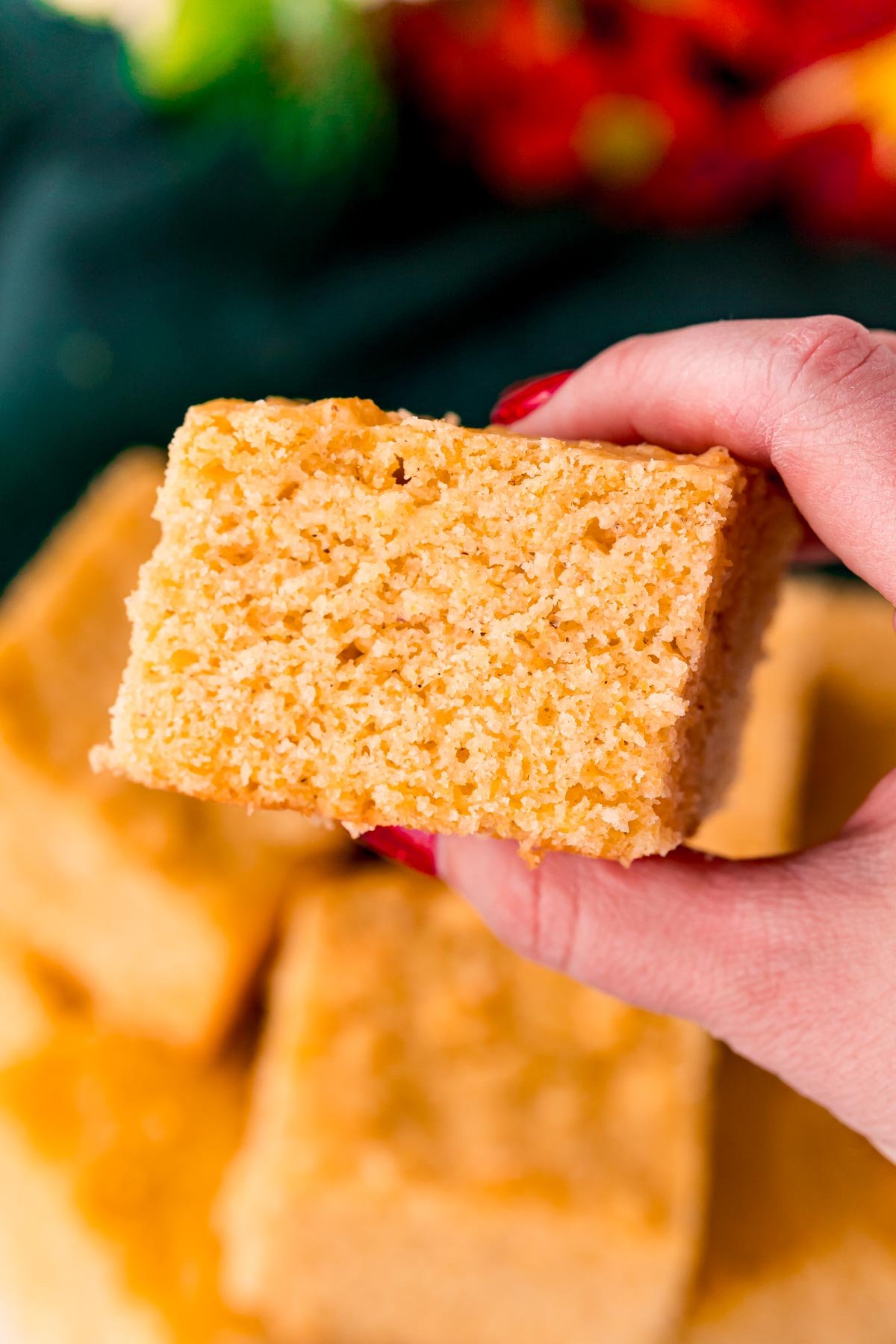 A woman's hand holding a slice of cornbread.