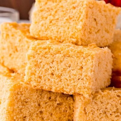 Close up photo of corn bread slices stacked on top of each other on a white plate.