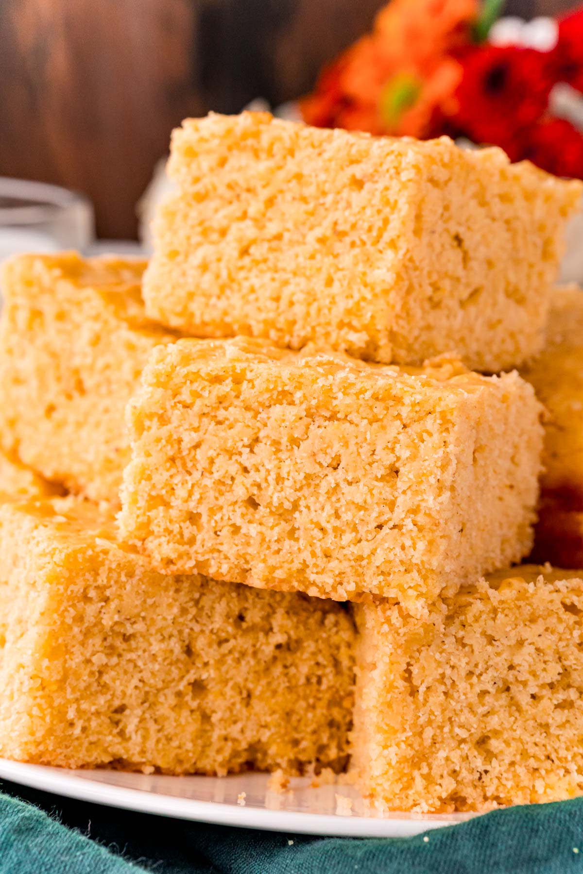 Close up photo of corn bread slices stacked on top of each other on a white plate.