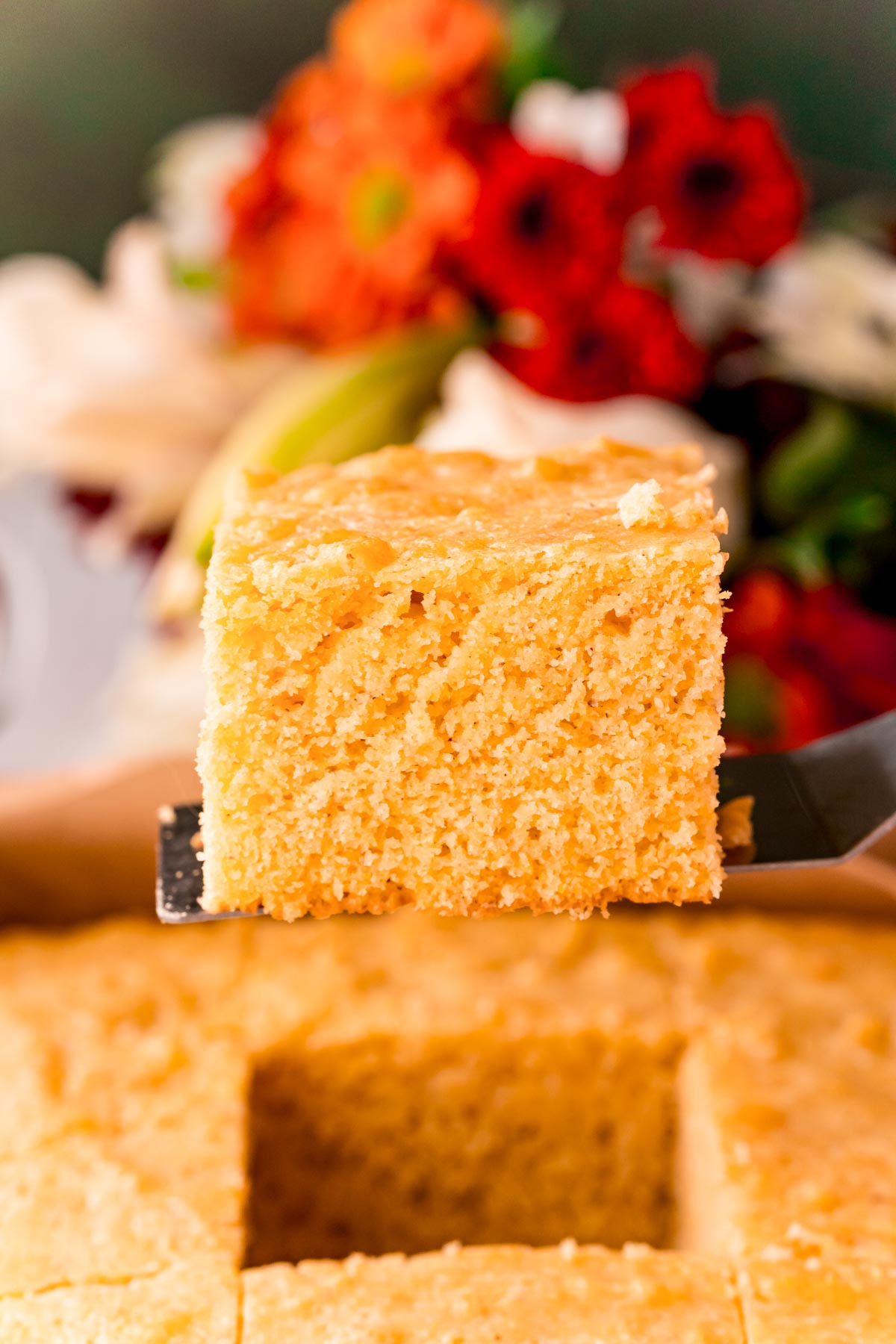 A slice of cornbread being lifted out of a baking pan.