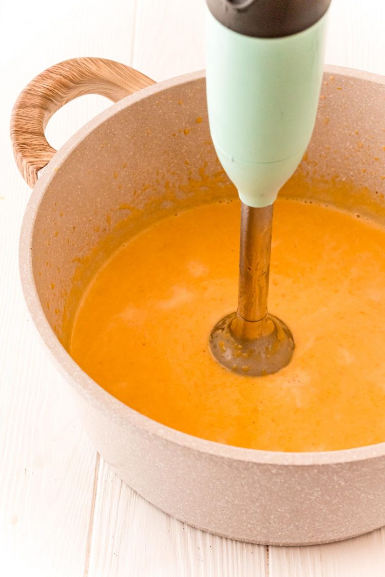 An immersion blender blending butternut cream sauce.