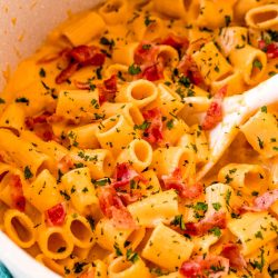 Butternut squash mac and cheese in a pot with a white serving spoon.