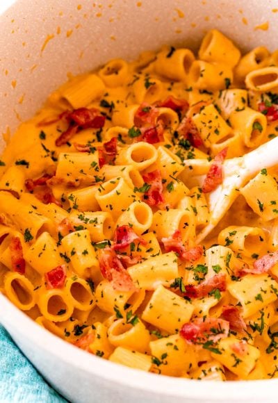 Butternut squash mac and cheese in a pot with a white serving spoon.