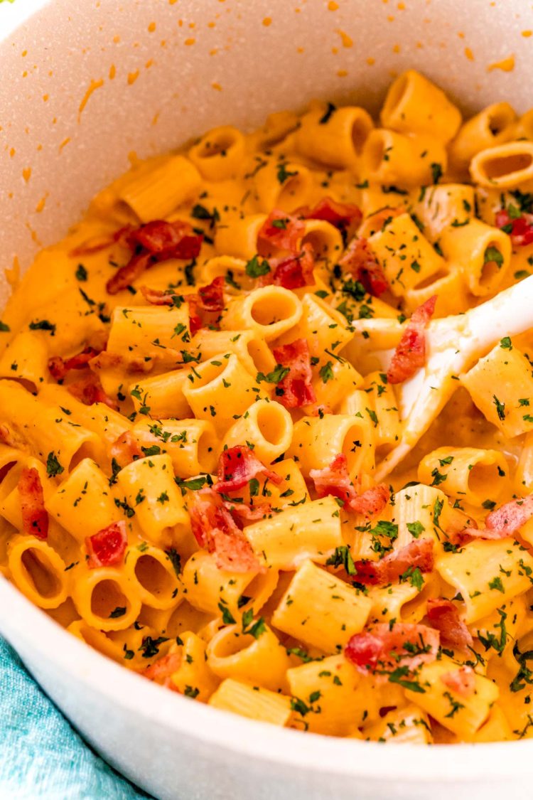 Butternut squash mac and cheese in a pot with a white serving spoon.